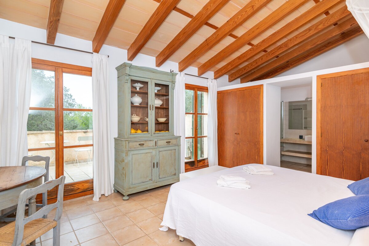 A bedroom with a dresser and a bed with white sheets