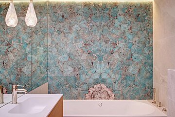 Stylish bathroom showcasing a vibrant turquoise and brown gemstone wall, alongside a white tub, sink, and decorative pendant lights.
