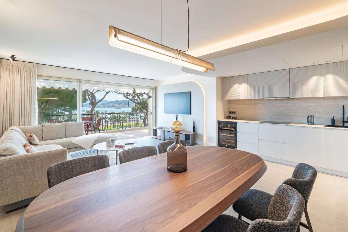 Sleek open-plan living space with kitchen, dining, and living room, boasting a balcony with a stunning sea view.