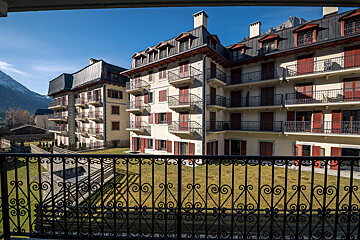 A balcony with a wrought iron railing overlooking a large building