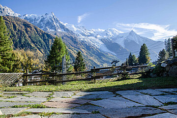 A fence surrounds a grassy area with mountains in the background