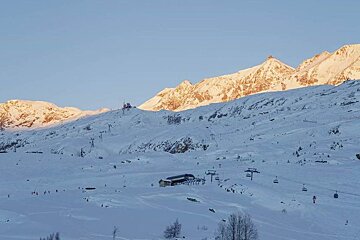 A snowy mountain with a blue house in the foreground