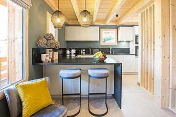 A kitchen with two stools and a bowl of bananas on the counter