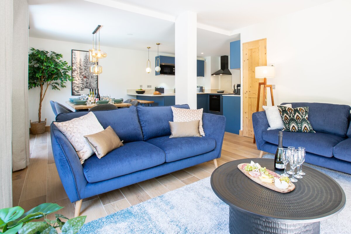 A living room with two blue couches and a coffee table