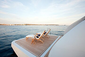 Two chairs are sitting on the deck of a boat in the ocean
