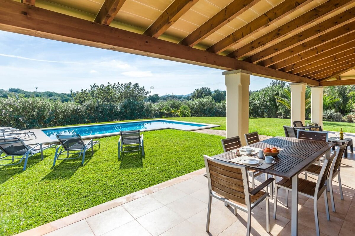 A patio with a table and chairs overlooking a swimming pool