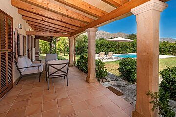 A patio with a couch and chairs and a pool in the background
