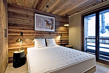 A bedroom with a picture of a deer on the wall above the bed