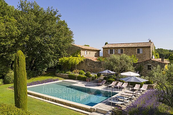 A large swimming pool surrounded by chairs and umbrellas with the word janssens in the corner