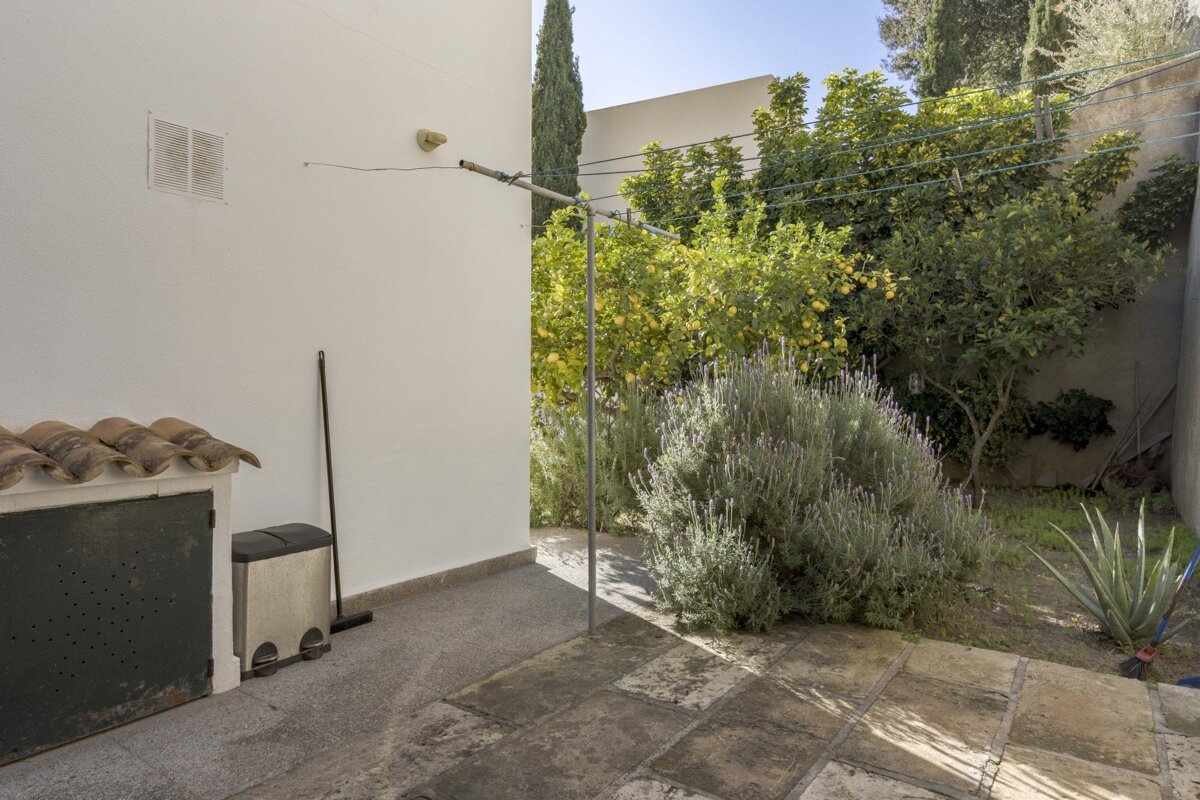A stainless steel trash can sits on the side of a building