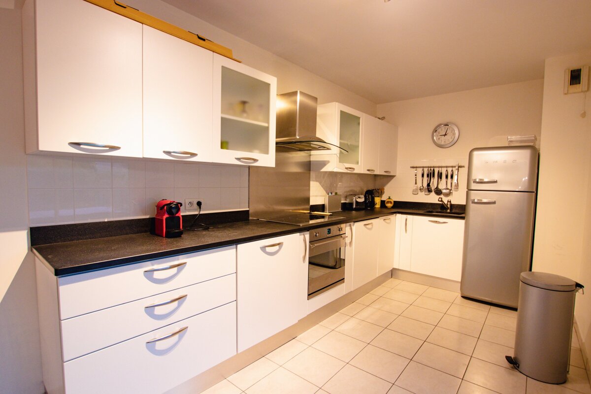 A kitchen with white cabinets and a silver refrigerator
