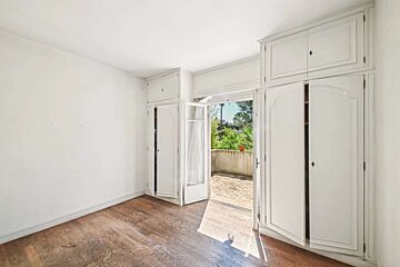 An empty room with white cabinets and a balcony