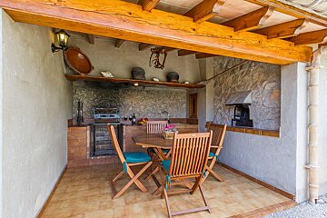 A wooden table and chairs under a wooden roof