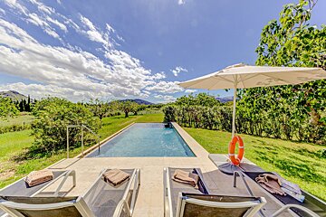 A swimming pool surrounded by chairs and a white umbrella