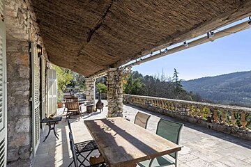 Rustic stone patio with natural woven shade, outdoor dining, and stunning mountain views.