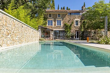 A large stone house with a large swimming pool in front of it