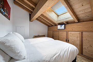 A bedroom with two beds and a flat screen tv