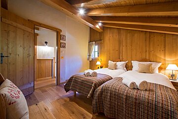 A wooden bedroom with two twin beds and lamps