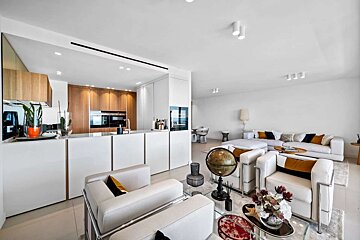 A modern, open-plan living room and kitchen with white and wood finishes, sleek furniture, and warm gold/black accents for a bright, sophisticated look.