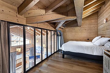 A bedroom with a large bed and lots of windows