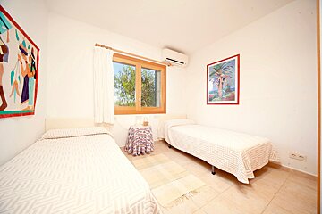A bedroom with two beds and a picture of a palm tree on the wall