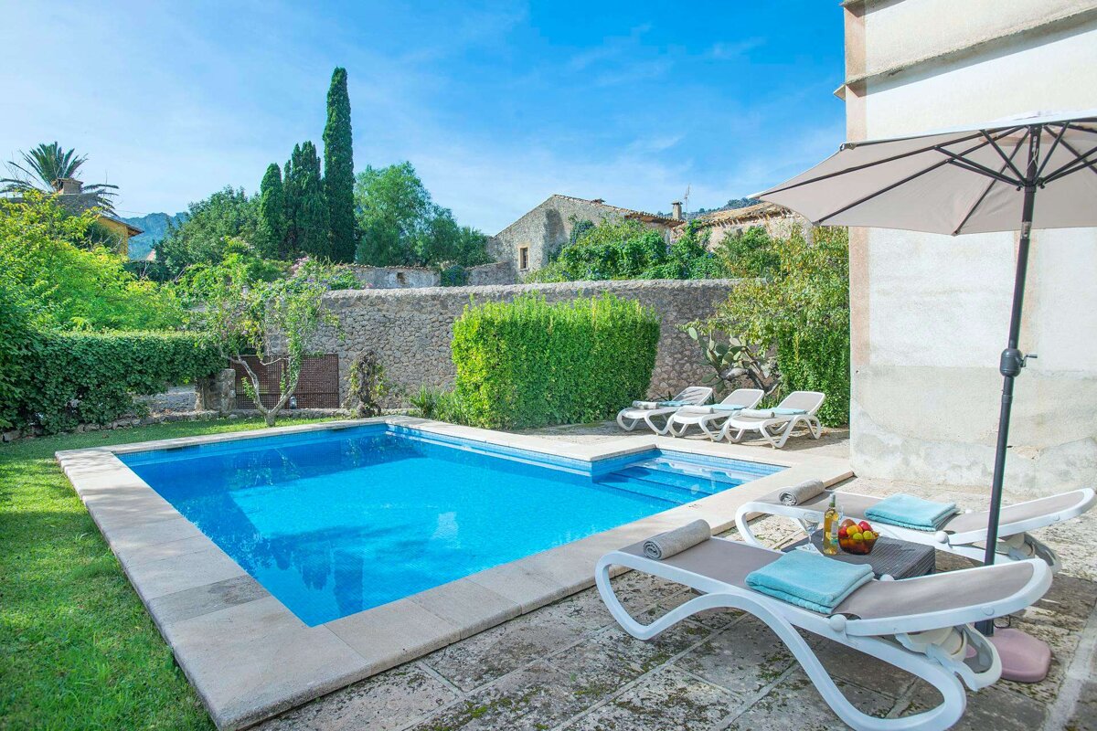 A swimming pool surrounded by chairs and an umbrella