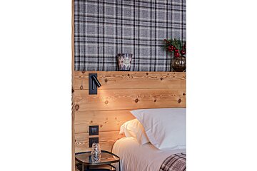 A bedroom with a wooden headboard and plaid wallpaper