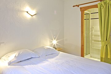 A bedroom with a white bed and green curtains