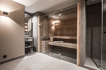 A bathroom with a glass door and a wooden sauna