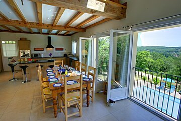 A dining room with a table and chairs and a view of a pool