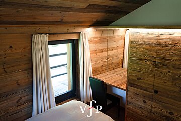 A bedroom with a bed and a desk with the letters vjp on the bottom