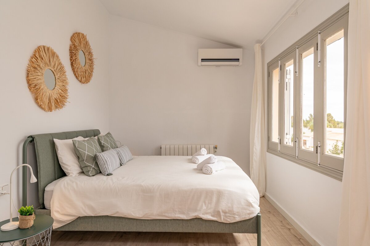 A bedroom with a bed and two mirrors on the wall