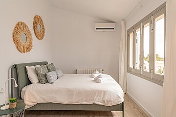 A bedroom with a bed and two mirrors on the wall