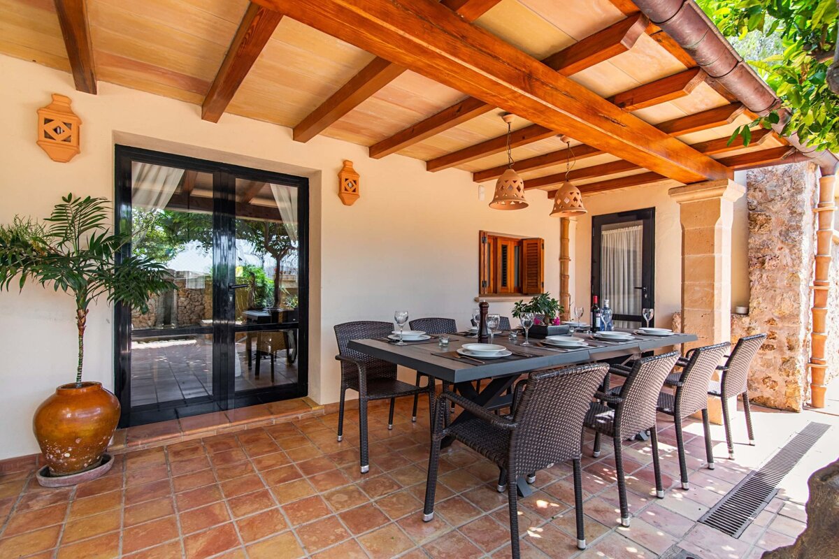 A patio with a table and chairs under a wooden roof