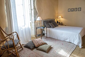A bedroom with a bed a chair and a rug