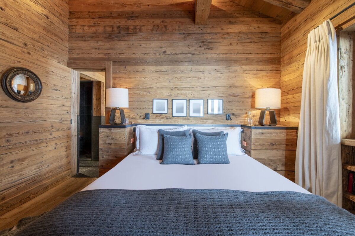 A bedroom with wooden walls and a bed