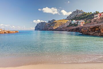 A beach with a mountain in the background and houses on the shore