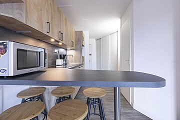 A kitchen with stools and a microwave that says nf on it