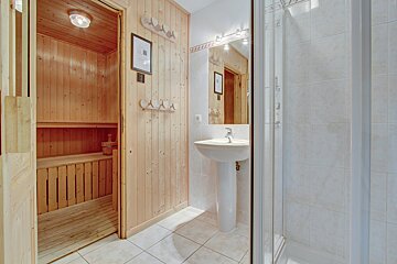 A bathroom with a wooden sauna and a sink