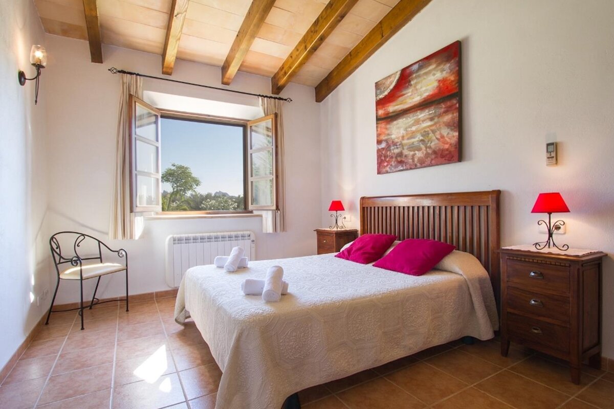 A bedroom with a painting on the wall above the bed