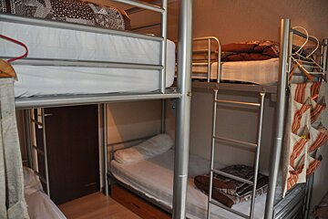 A bunk bed with a ladder between two other bunk beds