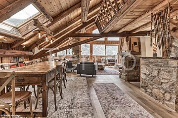 A wooden table and chairs in a room with a skylight
