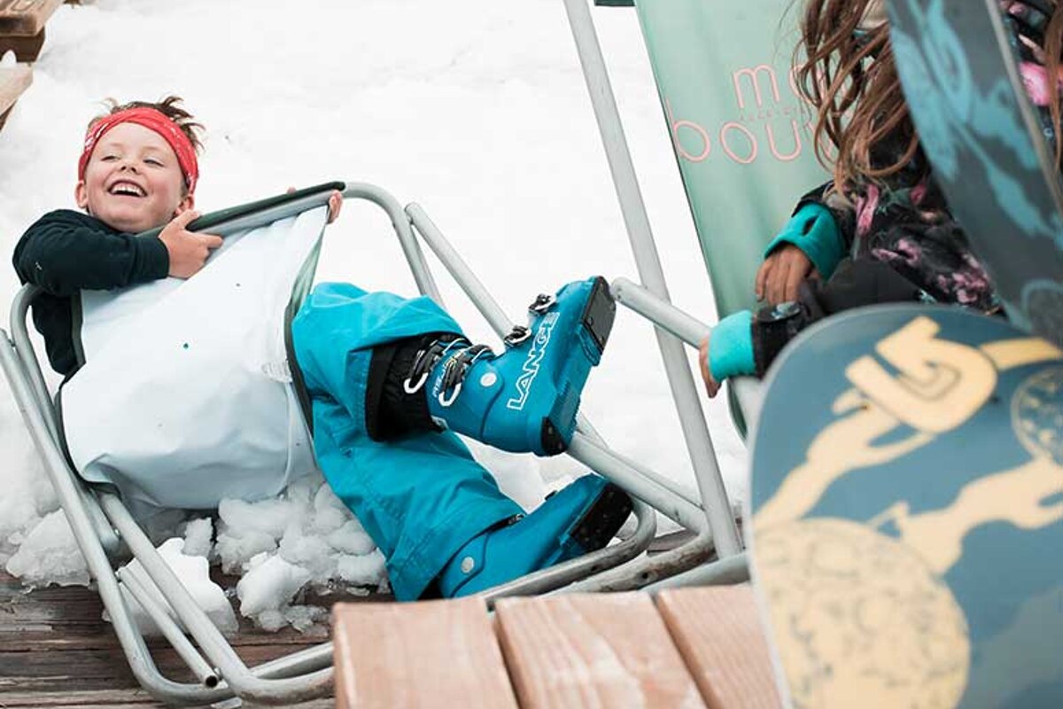 A child wearing blue la sportiva boots sits in a chair
