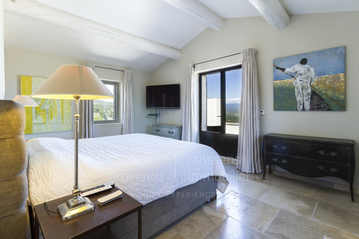 A bedroom with a large bed and a painting on the wall that says provence