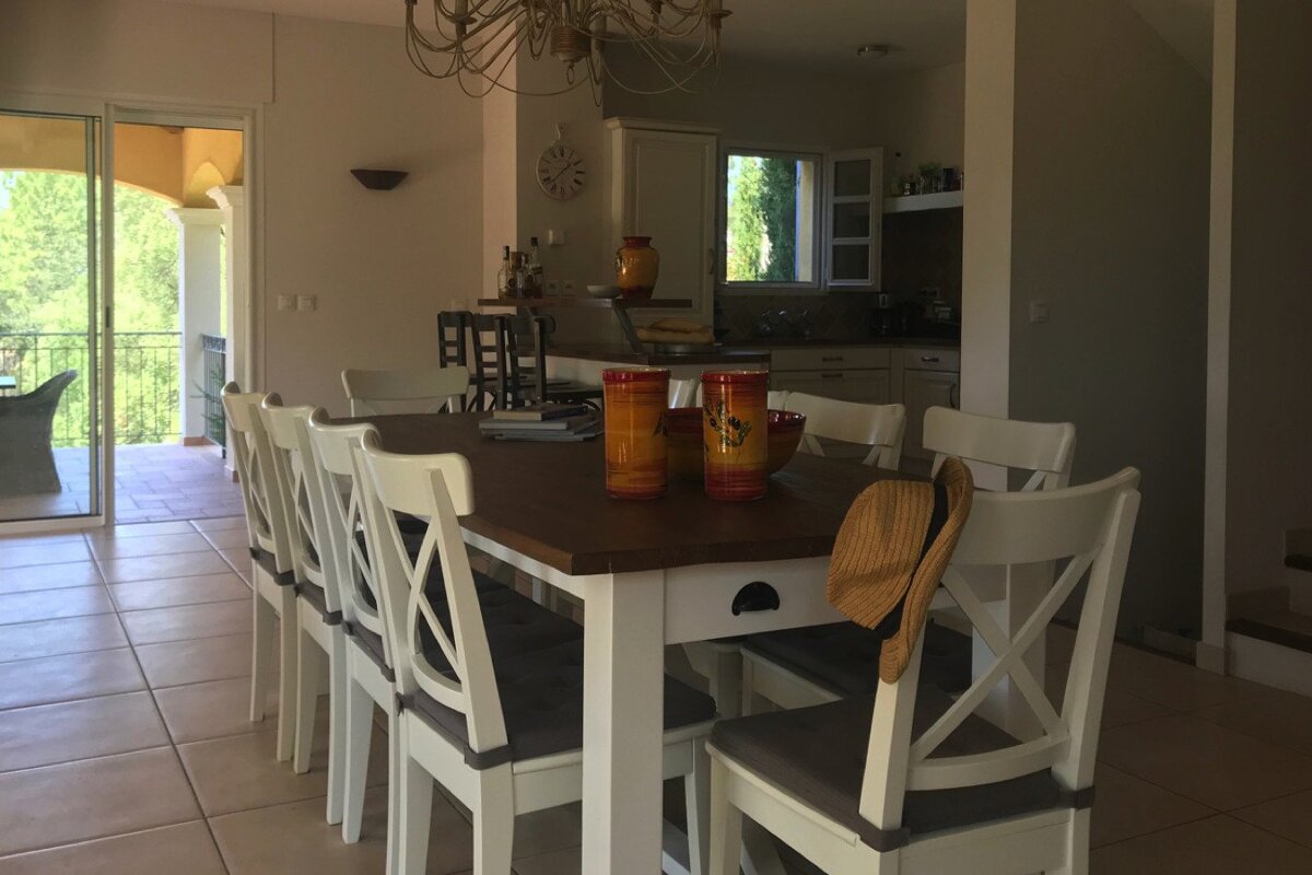 A dining room with a table and chairs and a clock on the wall