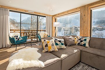 A living room with a couch and chairs and a view of the mountains