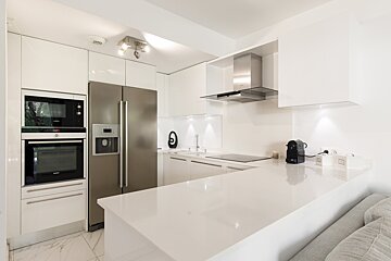 A kitchen with white cabinets and a stainless steel refrigerator