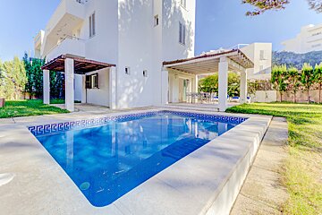 A white house with a swimming pool in front of it