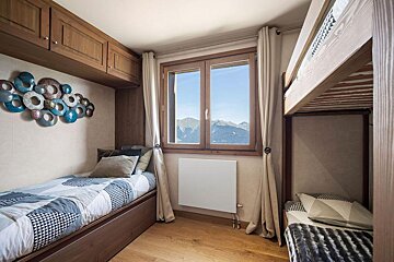 A bedroom with bunk beds and a window with mountains in the background