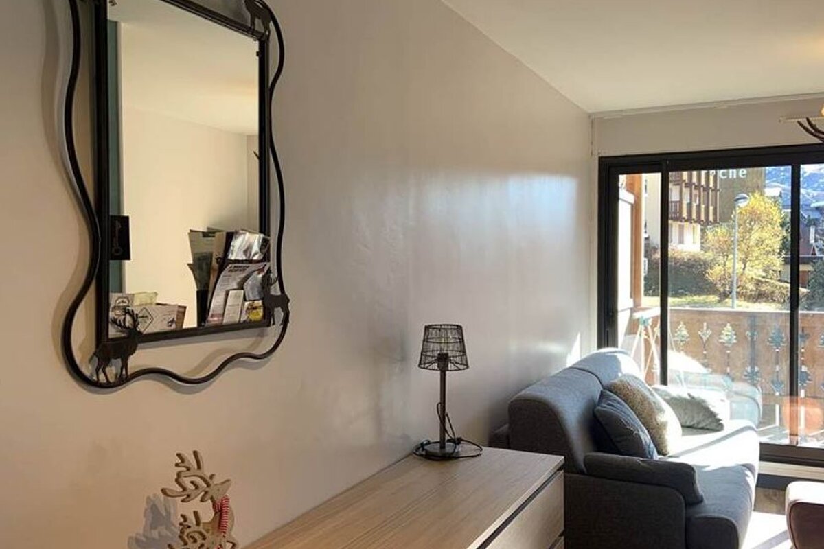 A living room with a couch a mirror and a lamp